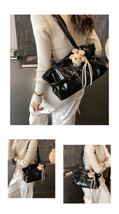 Close-up of black glossy tote bag featuring a plush bear charm and metallic buckle detail
