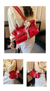 Detail of red patent leather tote bag with buckle design and plush bear charm decoration