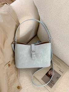Minimalistische hellblaue Schultertasche mit Marmortextur auf weißem Sofa mit Magazin
