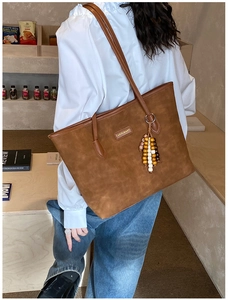 Detail view of large brown faux suede tote bag featuring a colorful beaded boho keychain charm