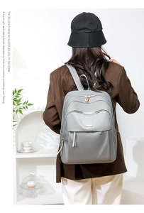 Detail shot of lightweight grey oxford backpack with adjustable straps and metal logo plate