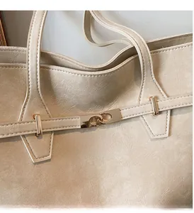Detail of elegant gold metal lock clasp on a beige leather tote bag with fine texture