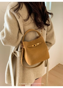 Rear view of a model styling a mustard yellow leather bucket bag with gold hardware