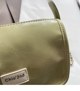 Détail du cuir texturé vert clair et de la plaque logo rectangulaire sur le sac