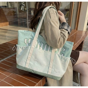 Detail of mint green canvas tote bag showing side drawstring pocket and VIBE print