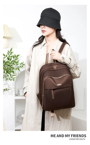 Close-up of deep brown nylon backpack featuring dual main zippers and gold metal logo plate