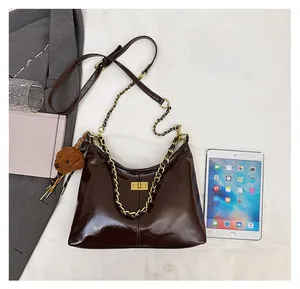 Detailansicht zum Größenvergleich der dunkelbraunen Kettenschultertasche mit Bärenanhänger