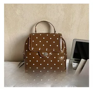 Detail shot of brown polka dot leather backpack with metal turn-lock and chain strap