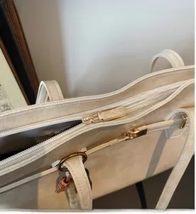Close-up of smooth metal zipper detail and fine texture on cream tote bag