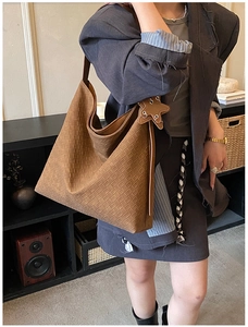 Detail of caramel woven leather hobo bag with star charm worn by a model in a studio