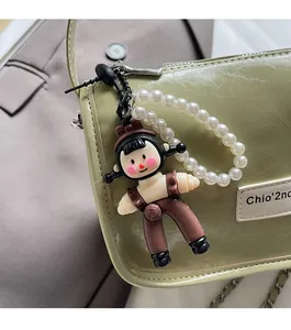 Détail d'un pendentif fille dessin animé mignon avec perles sur un sac à main vert