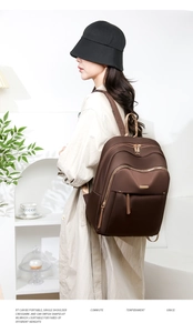 Detail of elegant dark brown Oxford fabric backpack with gold zippers shown on a model