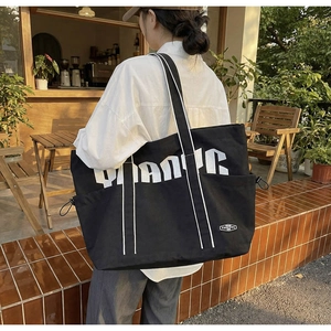 Detail of black canvas tote bag showing side drawstring pocket and durable fabric texture
