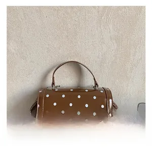 Top view of brown polka dot handbag featuring a curved handle and metal twist lock detail