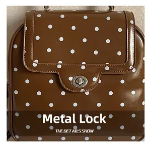 Close-up of the silver metal lock on a brown polka dot leather backpack for women