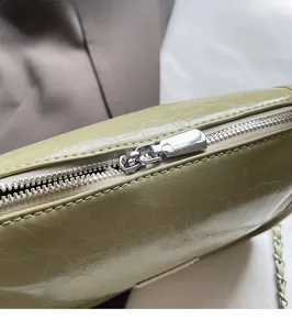 Détail de la fermeture éclair argentée et de la texture en cuir plissé vert du sac