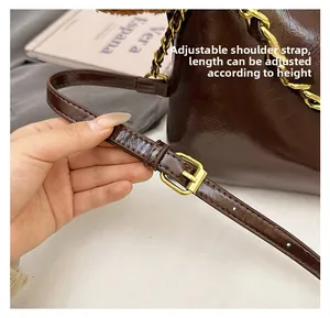Detail eines verstellbaren Lederriemens mit Goldschnalle und Kette an einer Retro-Tasche