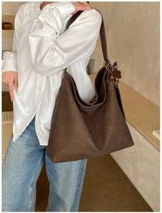 Detail of a brown woven hobo shoulder bag with a star charm on a minimalist background