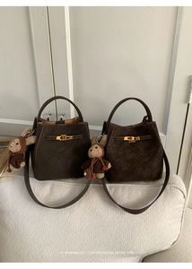 Detail view of brown suede bucket bag featuring a gold buckle and cute plush rabbit charm