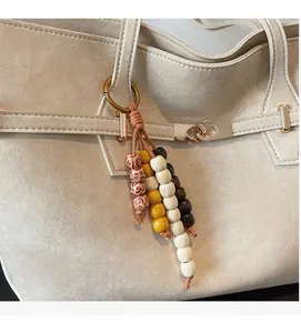 Close-up of ethnic beaded charm with wood and ceramic beads on a beige textured handbag