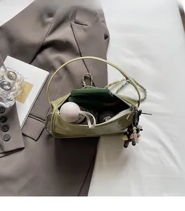 Vue détaillée du sac polochon en cuir verni vert montrant la capacité et la chaîne