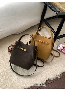 Detail of retro leather bucket bags with gold twist locks and plush bear charm