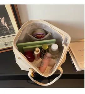 Detailed internal view of large beige tote bag holding a tablet and cosmetics