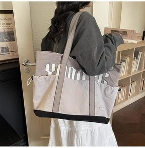 Detail of large capacity grey tote bag with white Yankees text and drawstring sides