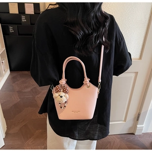Pink lychee grain bucket bag detail with plush bear charm and brand lettering