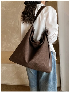 Detailed view of dark brown woven leather tote bag shoulder strap and texture on model