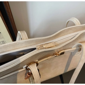 Close-up of metal zipper and textured fabric detail on a beige large tote bag