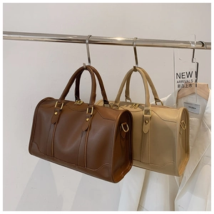 Detail of retro Boston handbags in brown and beige with dual handles and metal D-rings