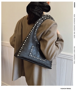 Detail of vintage black rivet shoulder bag in oil wax leather shown on model's shoulder