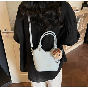 Detailed back view of a light blue lychee pattern shoulder bag with a plush bear charm