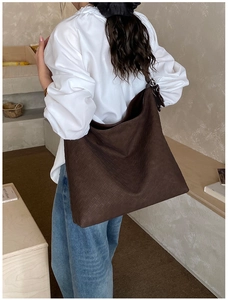 Detail view of a large dark brown woven leather tote bag shown in a stylish commute setting