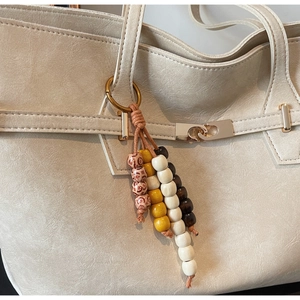 Close-up of colorful wooden bead keychain with metal ring on beige leather bag