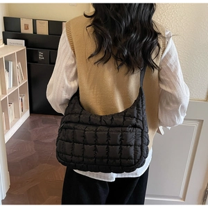 Détail du sac demi-lune noir matelassé avec une large bandoulière et fermeture éclair