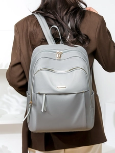 Chic grey oxford cloth backpack for women with gold zippers shown on a fashion model