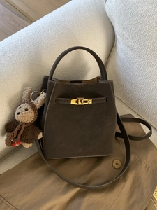 Deep brown bucket bag in matte leather featuring a gold swivel lock and rabbit charm