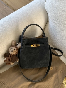 Elegant black leather bucket bag with top handle, gold hardware, and plush rabbit charm