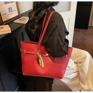 Close-up of red large capacity tote bag with buckle closure and beaded pendant detail