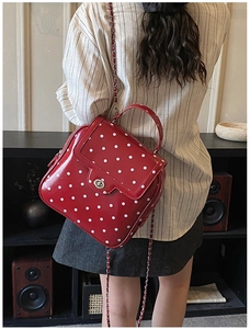 Detailed view of a red polka dot crossbody bag with chain strap and metal lock