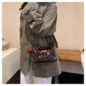 Detailansicht der glänzenden dunkelbraunen Lackleder-Schultertasche mit goldener Kette
