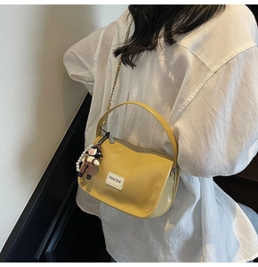 Détail du sac en similicuir jaune brillant avec chaîne de perles et pendentif