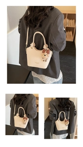 Close-up of cream leather bucket bag showing knotted handle and polka dot bear charm