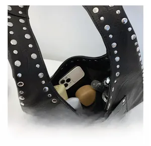 Detail view showing large internal capacity of black studded tote bag with lifestyle items