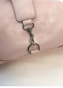 Close-up of pink textured leather bag with polished silver metal hook and D-ring