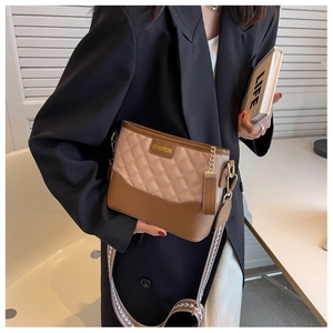 Dettaglio borsa a tracolla trapuntata beige e marrone con ampia tracolla in tessuto