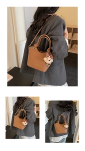 Close-up of brown leather bucket bag featuring round handle and plush bear charm detail