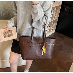 Detail of large brown tote bag showing vintage lychee texture and metal lock closure